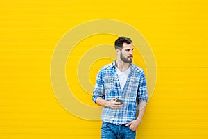 Young handsome man with headphones on yellow wall