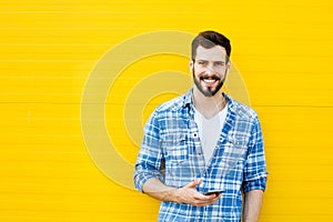 Young handsome man with headphones on yellow wall