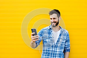 Young handsome man with headphones on yellow wall