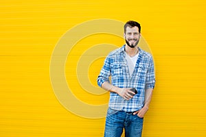 Young handsome man with headphones on yellow wall