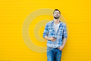 Young handsome man with headphones on yellow wall