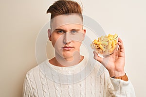 Young handsome man holding bowl with dry pasta standing over isolated white background with a confident expression on smart face