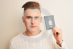 Young handsome man holding Canada Canadian passport over isolated white background with a confident expression on smart face