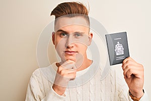 Young handsome man holding Canada Canadian passport over isolated white background serious face thinking about question, very