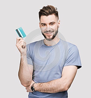 Young handsome man holding credit card isolated on white background. Online shopping, ecommerce, internet banking consept