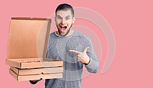 Young handsome man holding delivery italian pizza boxes smiling happy pointing with hand and finger