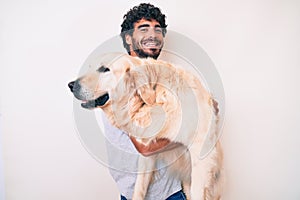 Young handsome man holding and hugging labrador retriever dog, smiling with love to his best friend