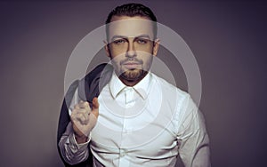 Young handsome man holding a jacket posing isolated over gray background.