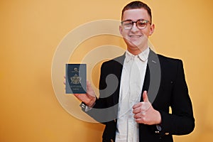 Young handsome man holding Saint Lucia passport id over yellow background, happy and show thumb up. Travel to America countries
