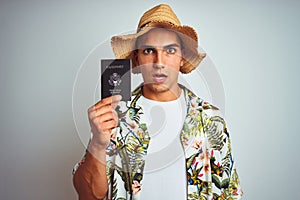 Young handsome man holding United States passport over white isolated background scared in shock with a surprise face, afraid and