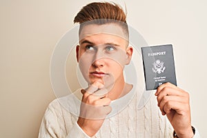 Young handsome man holding USA United States passport over isolated white background serious face thinking about question, very