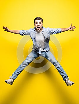 Young handsome man jumping on yellow background. Jump, freedom, summer.