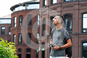 Young Handsome Man Launching Drone Quadcopter and Looking At It. Urban Stlilysh Contemporary Cityscape. Modern device