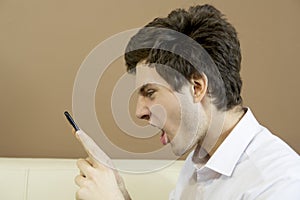 Man looks angrily at the smartphone. photo