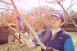 Young handsome man makes spring pruning