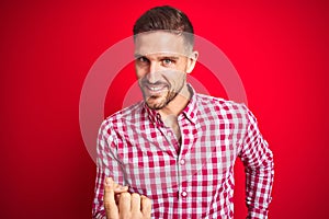 Young handsome man over red  background Beckoning come here gesture with hand inviting welcoming happy and smiling