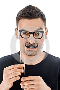 Young handsome man with paper moustaches and glasses making face