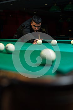 Young handsome man playing billiard game alone