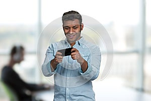 Young handsome man playing game on his smartphone.