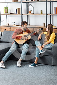 Young handsome man playing guitar for girlfriend in