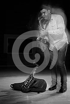 Young handsome man playing music on saxophone