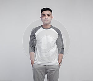 Young handsome man posing wearing raglan t-shirt with grey and white color isolated on background