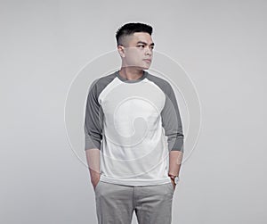 Young handsome man posing wearing raglan t-shirt with grey and white color isolated on background