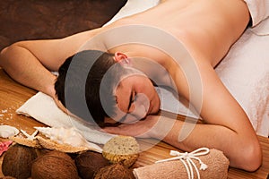 Young handsome man procumbent with spa decoration