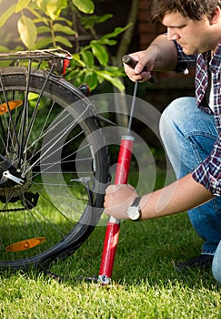 Young handsome man pumping bicycle tires at park