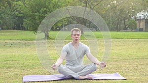 Young handsome man relaxing while meditating at the park