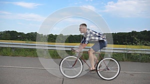 Young handsome man riding at vintage bicycle in the country road. Sporty guy cycling at the track. Male cyclist riding