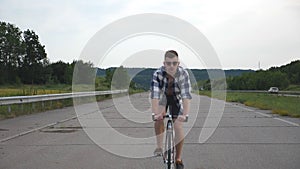 Young handsome man riding at vintage bicycle in the country road. Sporty guy cycling at the track. Male cyclist riding