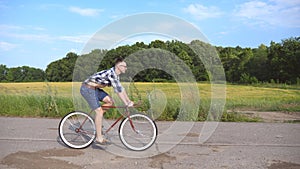 Young handsome man riding at vintage bicycle in the country road. Sporty guy cycling at the track. Male cyclist riding