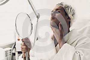 Young Handsome Man in Robe Loking into Mirror.