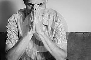 Young handsome man in the shirt cover his face with his hands feeling depressed and miserable while he thinking about life.