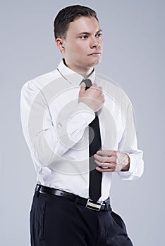 Young handsome man in a shirt with a tie on a light gray background