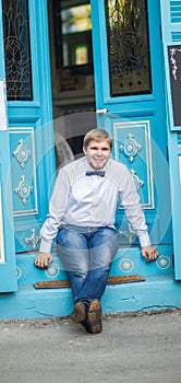 Young handsome man with short hair wearing a bow tie and posing in the city streets.