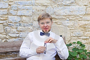 Young handsome man with short hair wearing a bow tie and posing in the city streets.