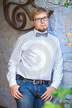 Young handsome man with short hair wearing a bow tie and posing in the city streets.