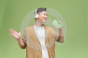 Young handsome man singing his favorite song, using a smartphone as a microphone