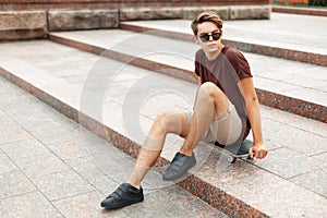 Young handsome man sitting on a skateboard