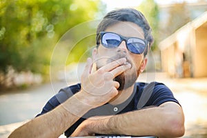 Young handsome man smokes with his hands on vintage tape recorder