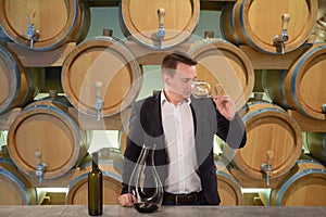 Young handsome man sommelier tasting red wine in wine cellar