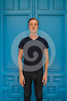 Young handsome man standing in front of blue door