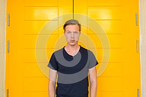 Young handsome man standing in front of yellow door