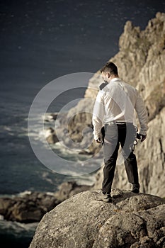 Young handsome man standing on rocks overlooking ocean