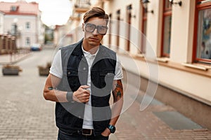 Young handsome man in stylish glasses in vintage denim vest