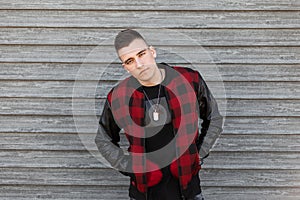 Young handsome man with a stylish hairstyle in a trendy black T-shirt in a stylish red checkered jacket with leather sleeves