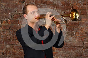 Young handsome man in suit plays trumpet in studio
