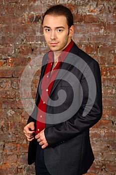 Young handsome man in suit and red shirt poses in